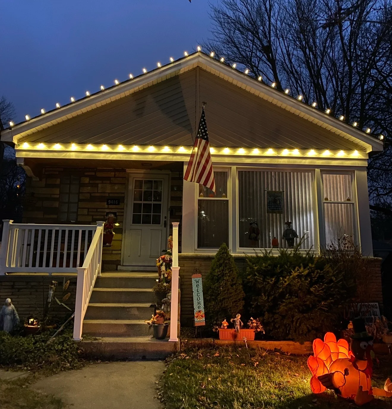 Warm-white roofline and porch lights on a single-story home at dusk