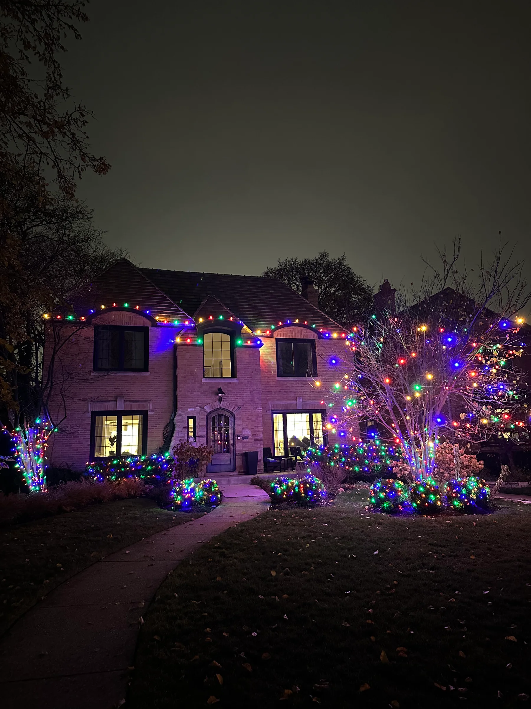 Colorful roofline and landscape lighting on a brick home