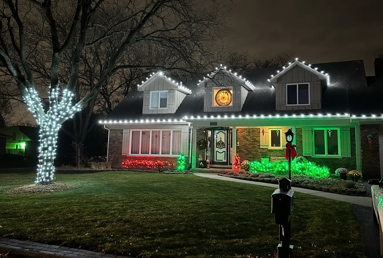 Red, green, and cool-white custom holiday lighting across a home and yard