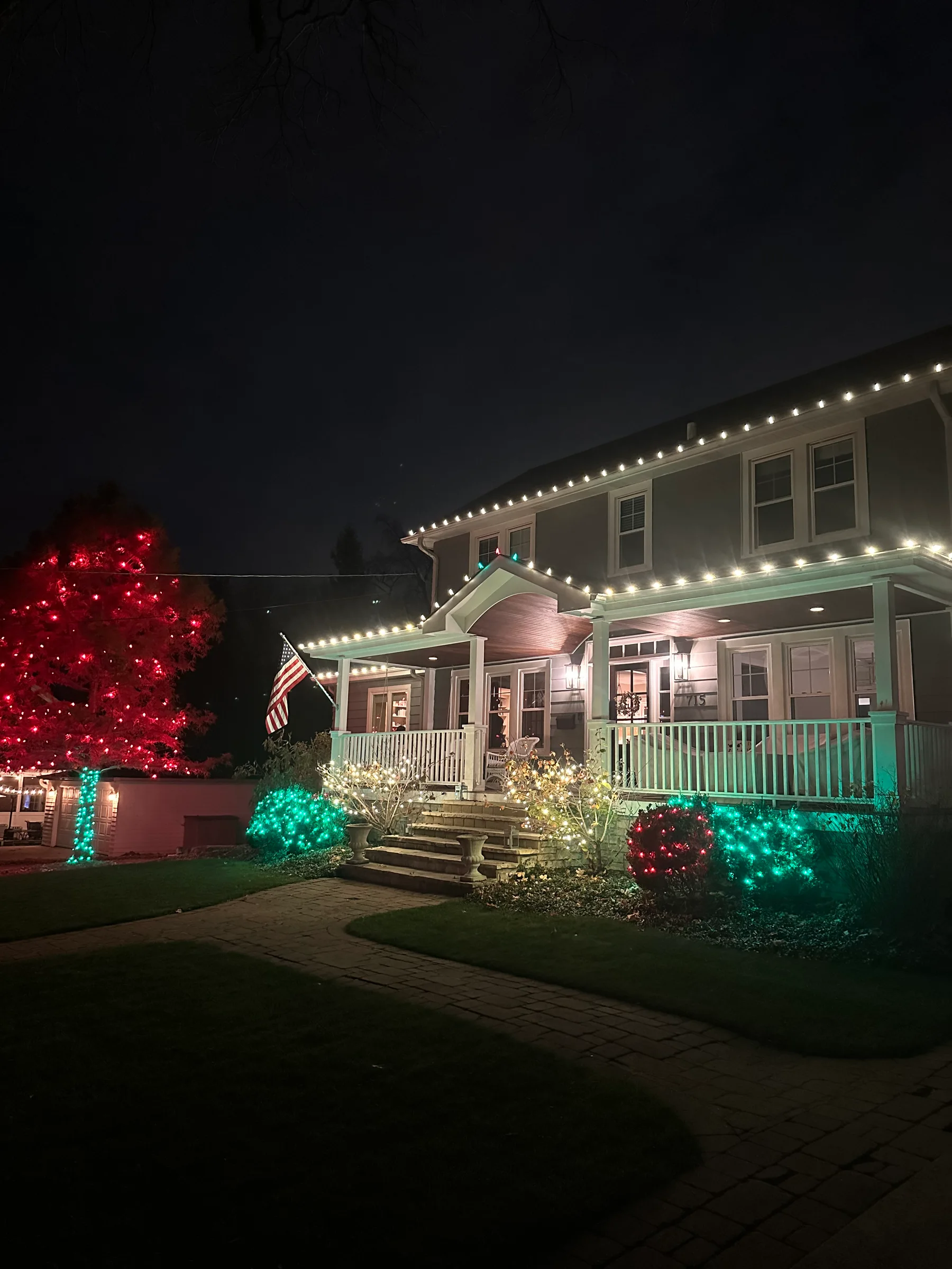 Classic porch home with warm white roofline and red and green landscaping